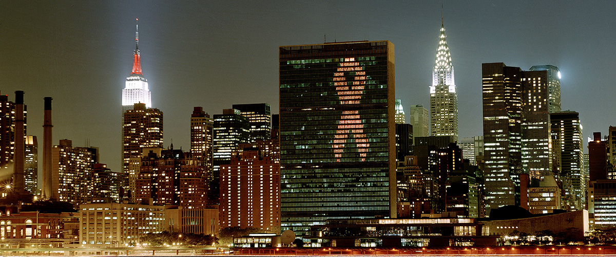 Красная ленточка — символ борьбы со СПИДом — на фасаде здания Секретариата ООН в Нью-Йорке, июнь 2001 года. Фото: ООН/Эскиндер Дебебе